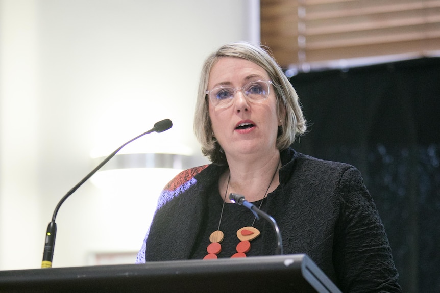 A woman delivers a speech at a lectern.