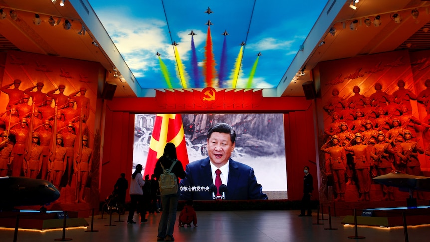 Image of Xi on screen with graphic of warplanes flying above in museum