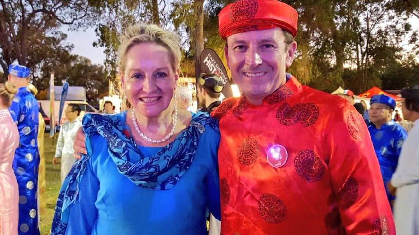 Alannah McTiernan and Mark McGowan pose for the camera wearing traditional blue and red Vietnamese outfits.