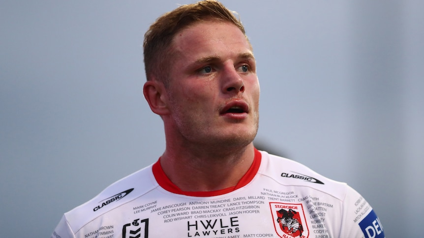 A man in a white football jersey with close cropped hair