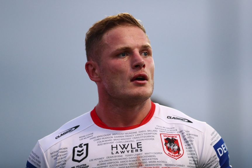 A man in a white football jersey with close cropped hair