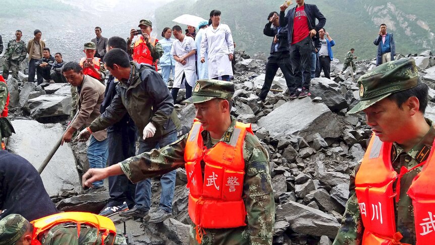 Emergency personnel and local people work at the site of a landslide in Xinmo village, southwestern China.