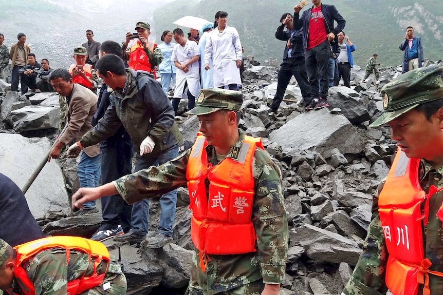 Emergency personnel and local people work at the site of a landslide in Xinmo village, southwestern China.