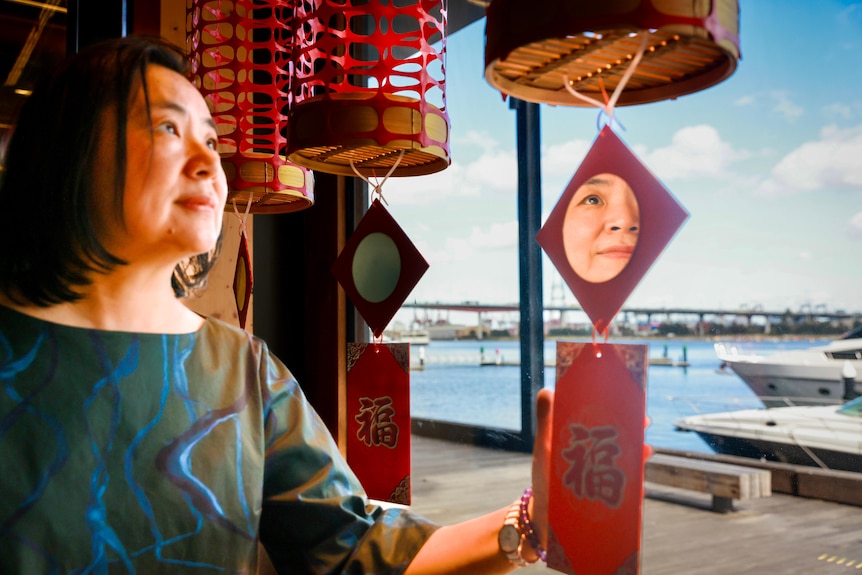Jenny holding a red pocket with the Chinese word 'fu' that hangs beneath the lantern.