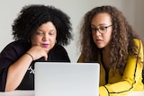 Two women looking at computer in a story about using a financial accountability partner to reach money goals.