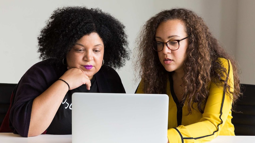 Two women looking at computer in a story about using a financial accountability partner to reach money goals.