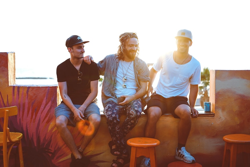 Three men sit together on a balcony