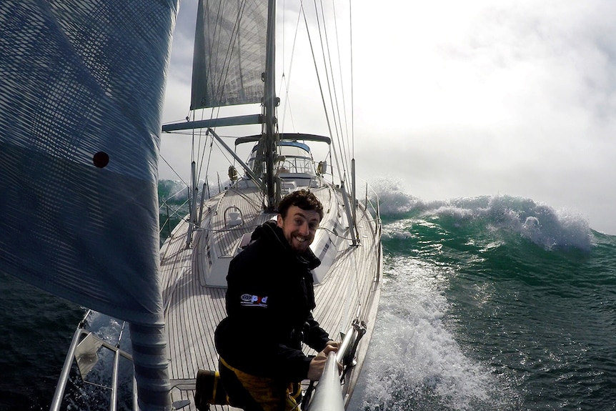 Irish sailor Gregor McGuckin smiles for a selfie photo sailing in big seas on a yacht.