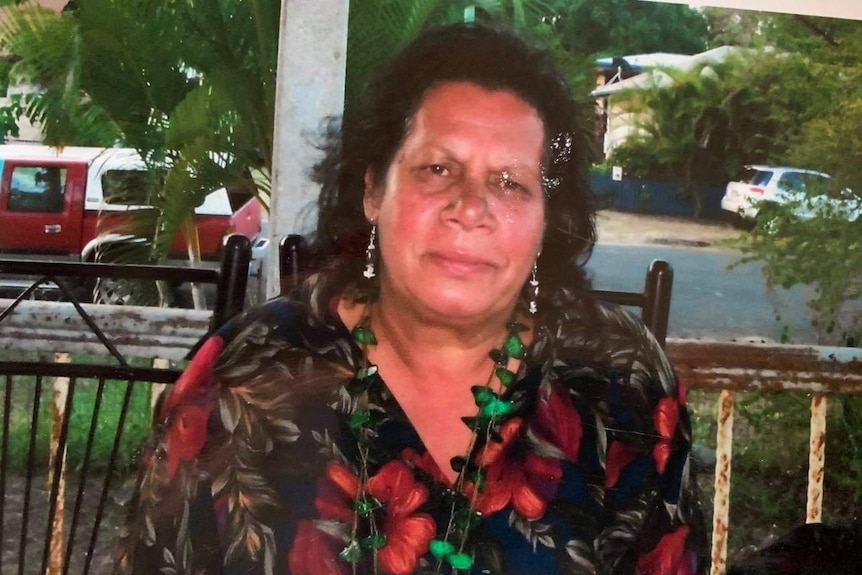 An Indigenous woman sitting on a porch.