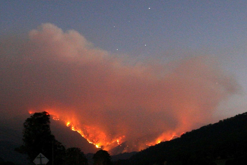 Flames from bushfire light up early evening sky.