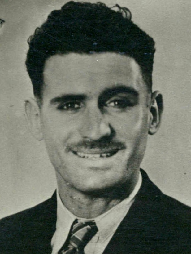 A black and white photo of a smiling man with a good head of hair and a mustache.