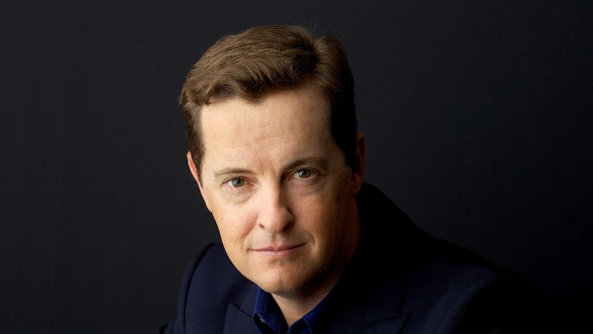 Portrait of author Matthew Reilly on a dark blue background