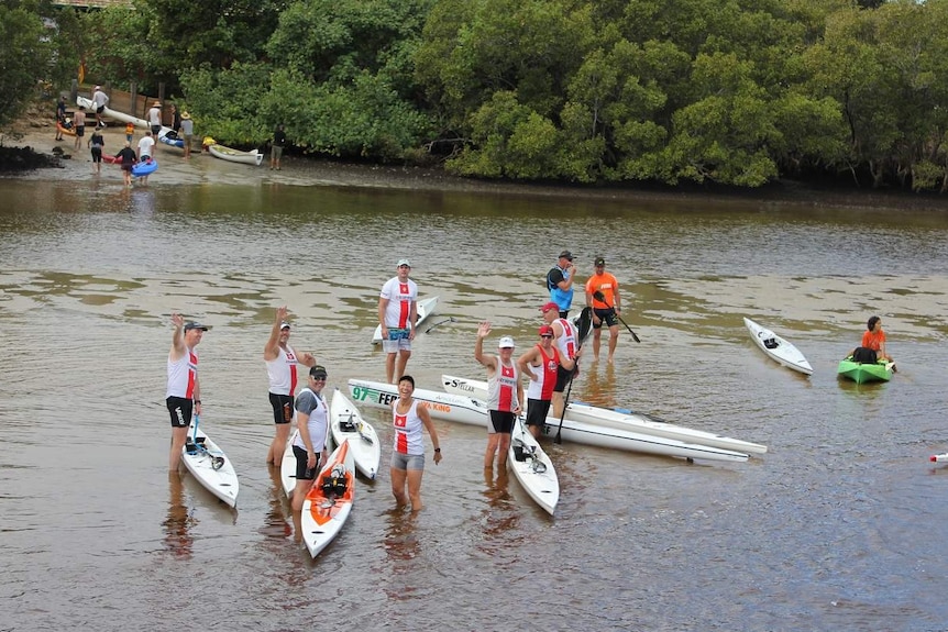 Group of people stand near kayaks smiling