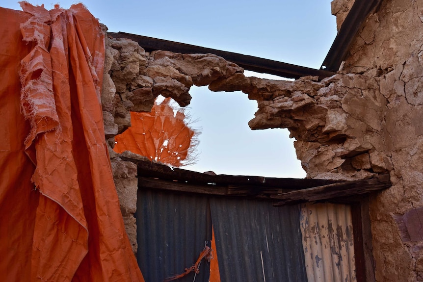 Stone above a door-way hangs precariously above a hole which has developed. Rusted steel holds the doorway up