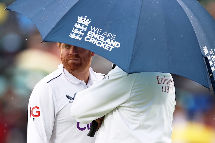 England wicketkeeper Jonny Bairstow stands under an umbrella with an umpire during an Ashes Test at The Oval.