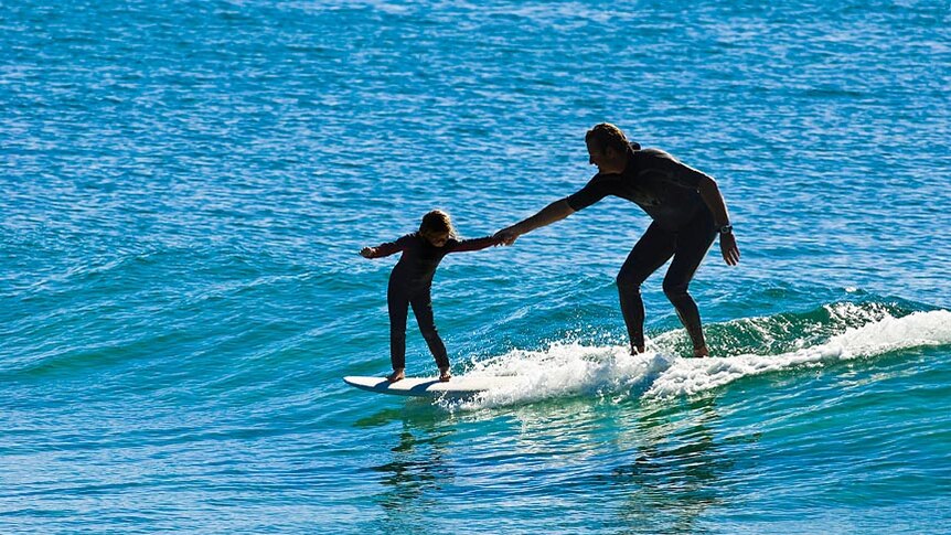 A man and his daughter share a ride on a wave at Scotts Head.