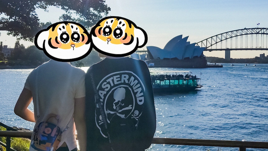 Two men standing together with the Sydney Harbour Bridge in the background (their faces are not shown).