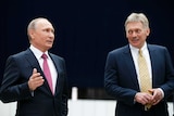 Russian President Vladimir Putin stands with his press secretary.