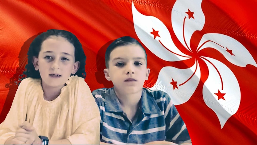 A boy and a girl sit in front of a Hong Kong flag.