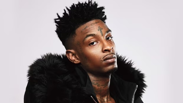 A head and shoulders photo of 21 Savage in a black jacket with a black fur lining