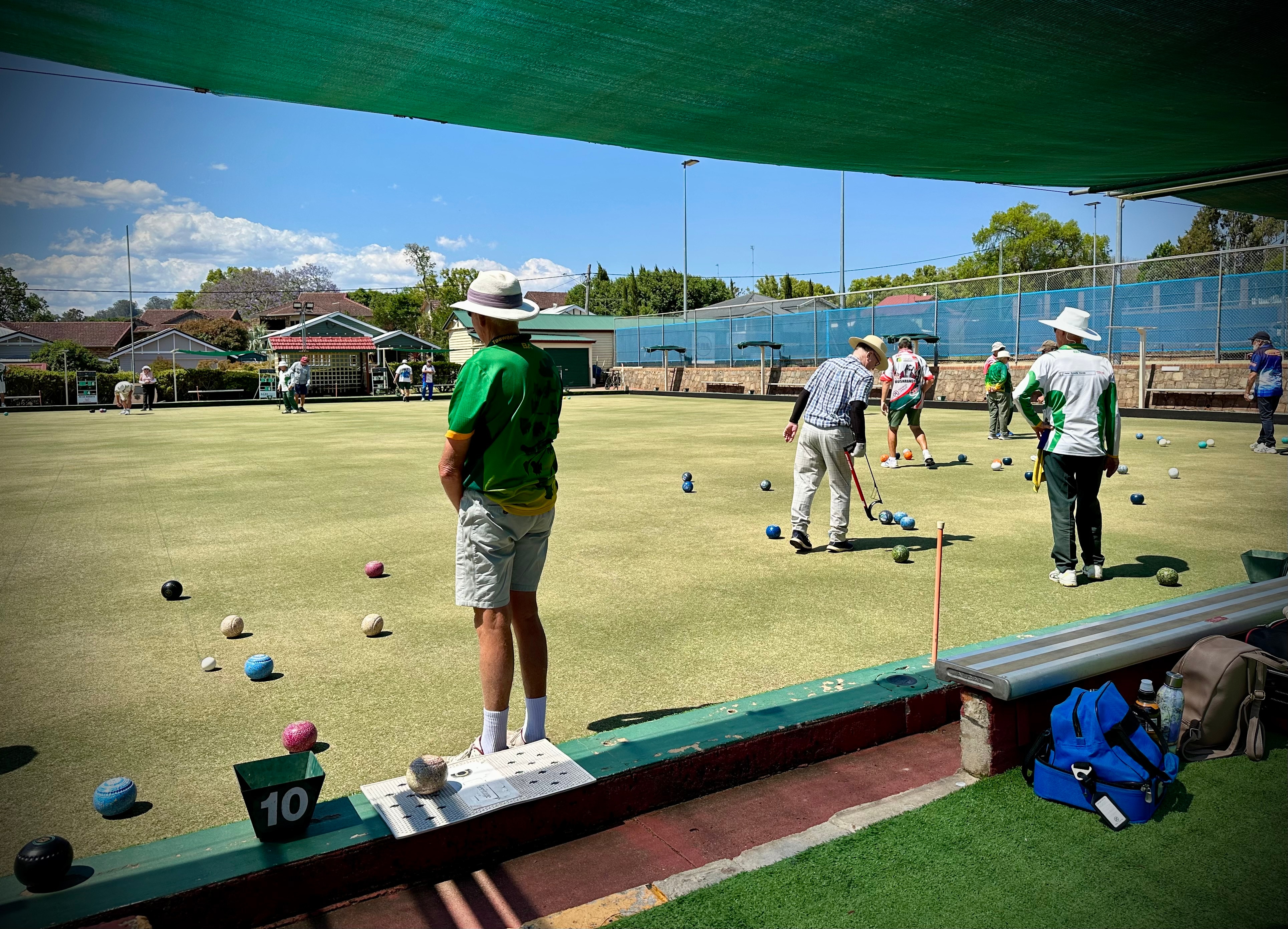 A few people stand on a green playing lawn bowls