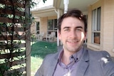 Selfie of a man standing in front of his house 