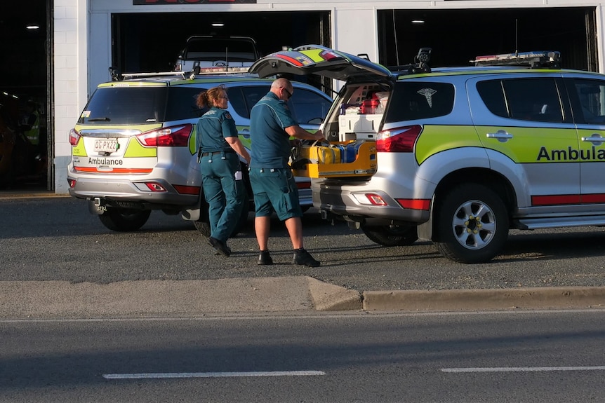 Two ambulance vehicles parked out the front of a mechanic.
