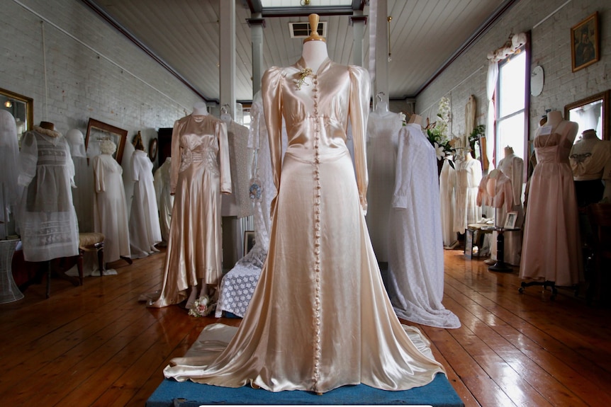A museum room with a many wedding dresses on display 