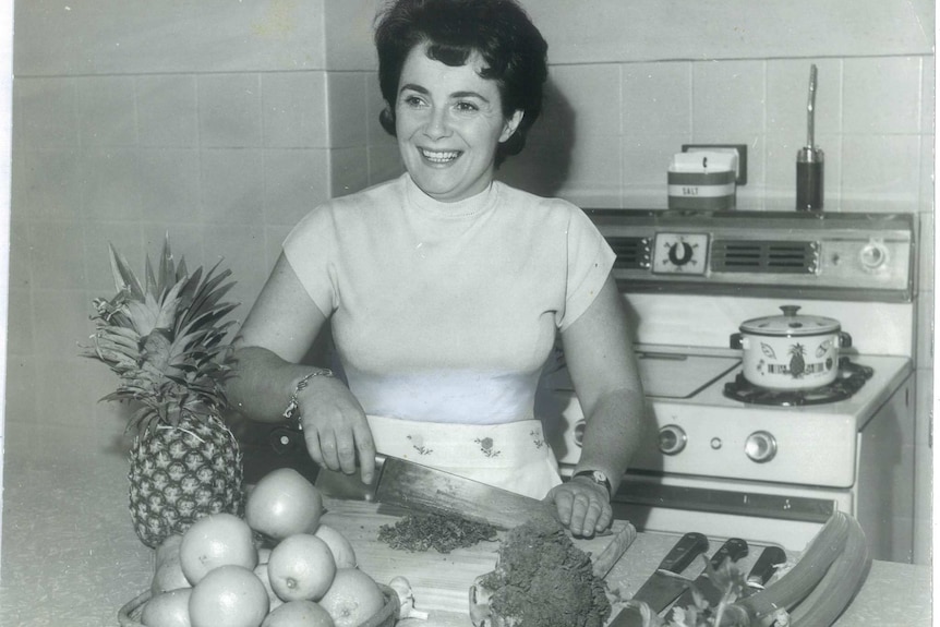 Black and white image of woman cutting broccoli