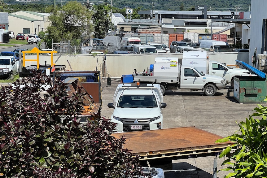 An industrial yard with a truck trailer and several parked utility vehicles.