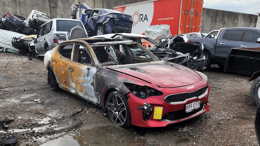 Burnt out car sits in car yard. 