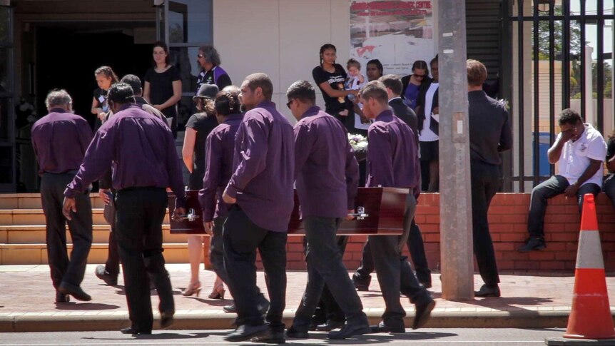 Pallbearers carry a coffin into a funeral service in Leonora.