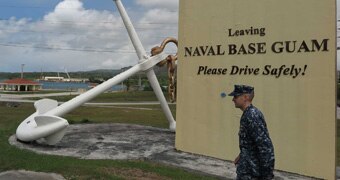 A US soldier walks past a sign for the Naval Base Guam.