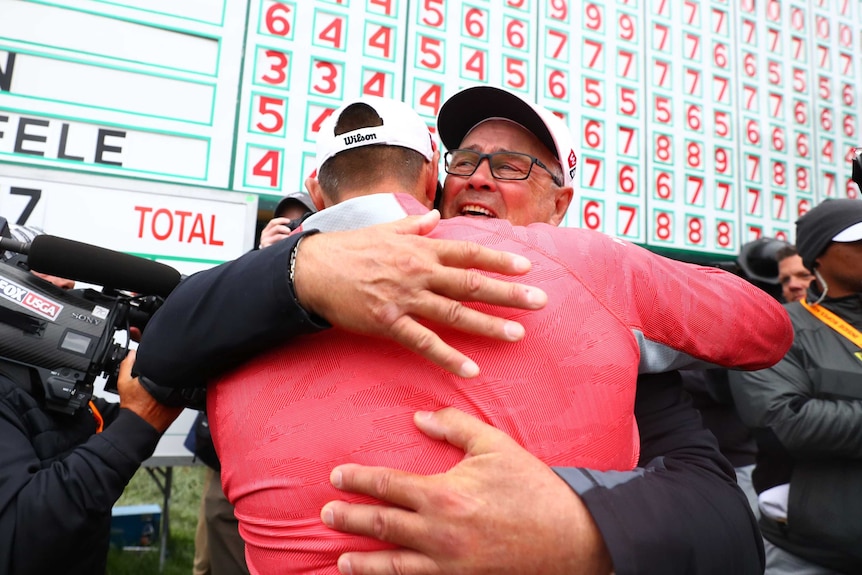 Gary Woodland hugs his father in front of the main scoreboard at Pebble Beach