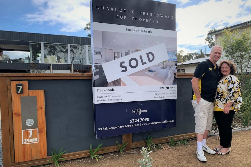 Steve and Annette Bourke stand in front of a sold sign outside of their property at Seven Mile Beach.