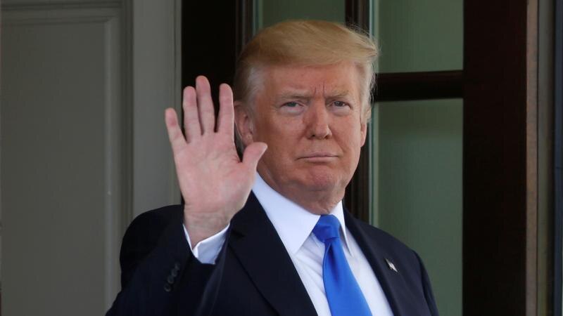 Donald Trump in a suit waves