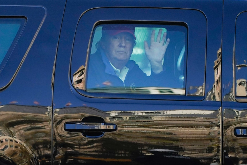 President Donald Trump waves to supporters from inside his motorcade.