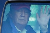 President Donald Trump waves to supporters from inside his motorcade.
