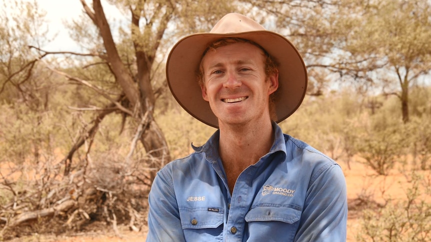 Grazier Jesse Moody smiles at camera in a dry paddock on his Cunnamulla property