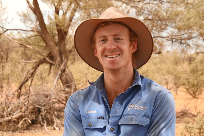 Grazier Jesse Moody smiles at camera in a dry paddock on his Cunnamulla property