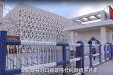 Employees walk through the gates at Golden Future's factory in Xinjiang. It is a big cube building with triangle windows.