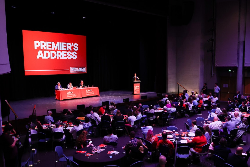 A backdrop that says "Premier's Address" over a stage in an auditorium.