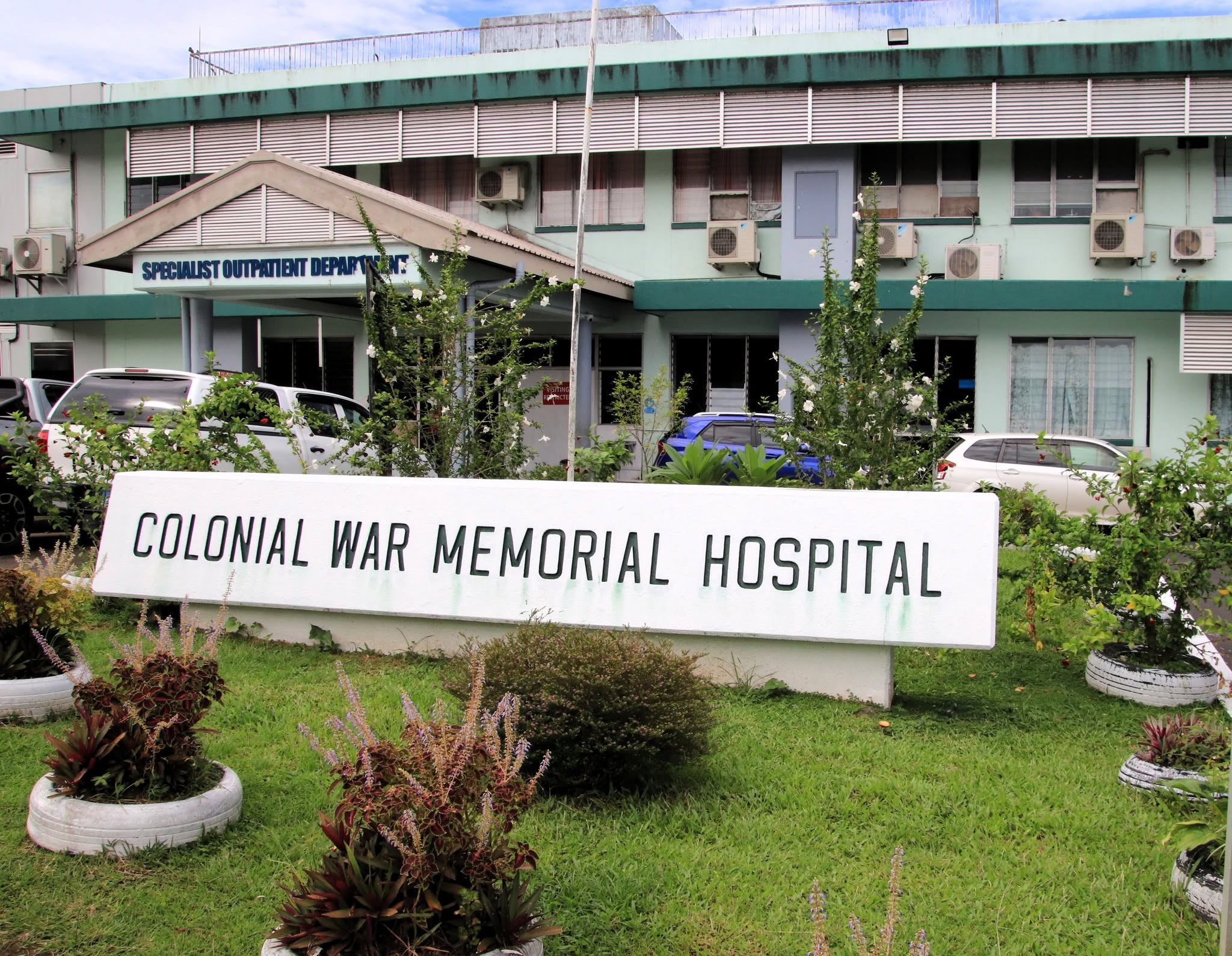 A hospital with a sign out front.