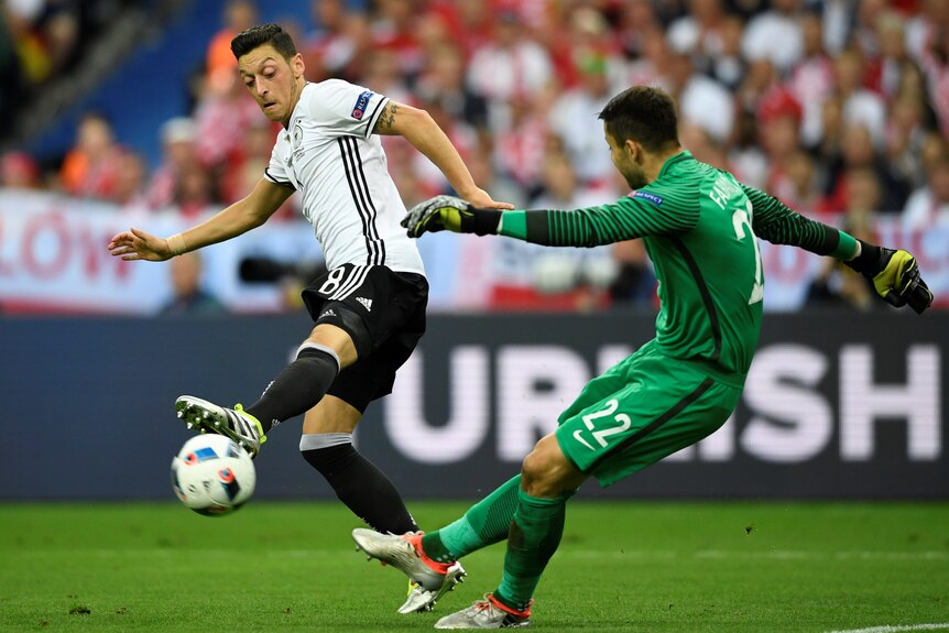 Lukasz Fabianski clears the ball under pressure from Mesut Ozil