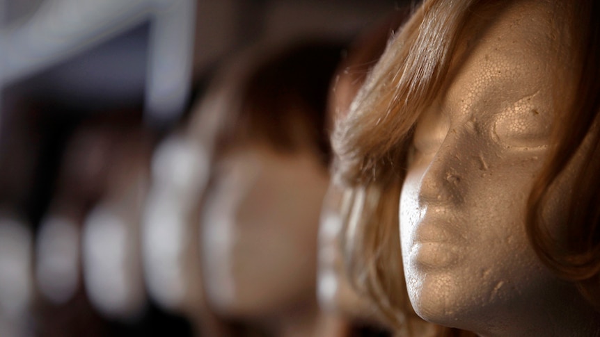 A close up of a styrofoam mannequin wearing a long brown wig.