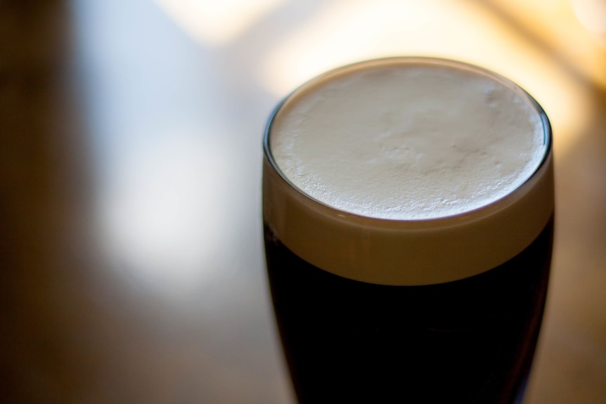 Close-up of a pint of stout with a foamy head.