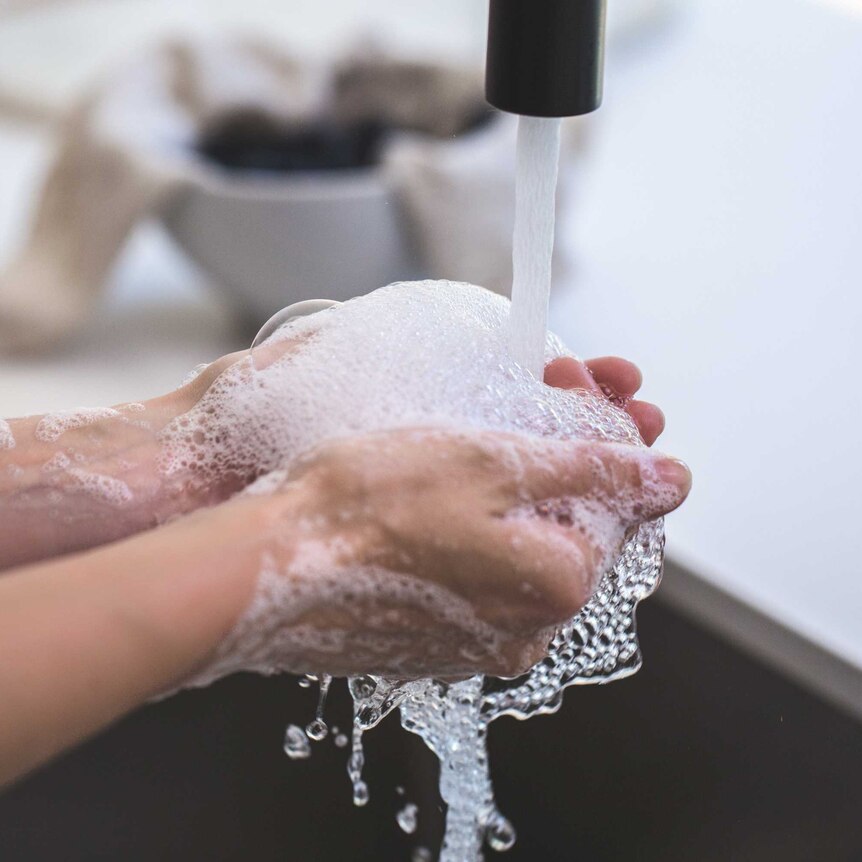 A person washes their hand at a sink.