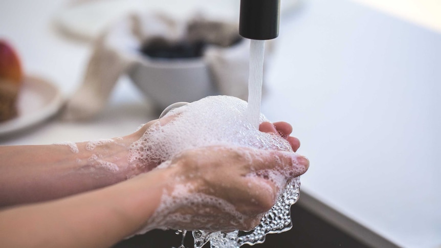 A person washes their hand at a sink.