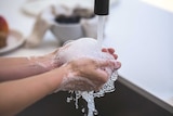 A person washes their hand at a sink.