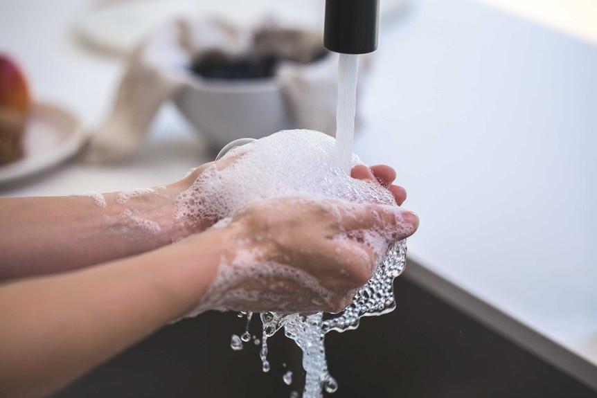 A person washes their hand at a sink.